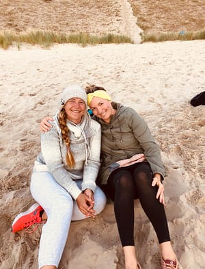 Zwei Frauen sitzen am Strand.